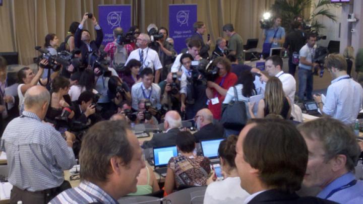 Photographers surround Peter Higgs, the theoretical physicist who proposed the existence of the Higgs boson