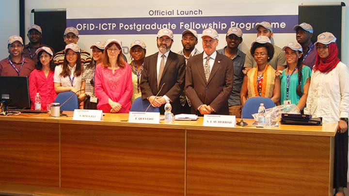 ICTP DIrector Fernando Quevedo (centre, left) and OFID Director-General Suleiman Jasir Al-Herbish (centre, right) and the Postgraduate Fellows pose with baseball caps donated by OFID